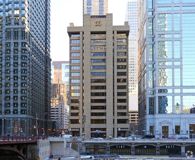 A tall concrete building with the number 55 in gold at the top of the face of the building.